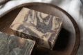 pexels-photo-6621338-6621338 From above of multicolored homemade soaps band ceramic bowl of coffee scrub placed on white fabric in daytime